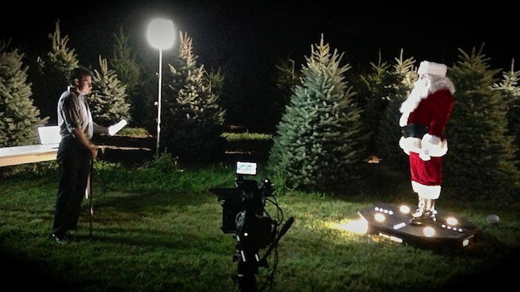Behind the scene with Santa Claus and man talking outside in a field of trees
